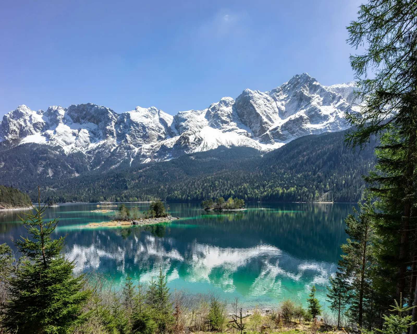 Eibsee mit türkisem Wasser und der verschneiten Zugspitze im Hintergrund