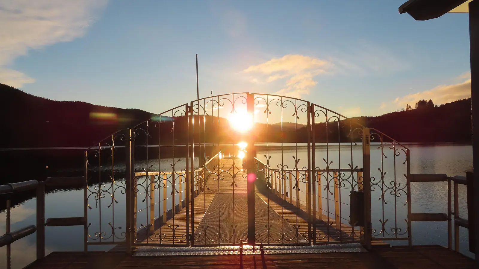 Anlegesteg mit schmiedeeisernem Tor am Titisee bei Sonnenuntergang