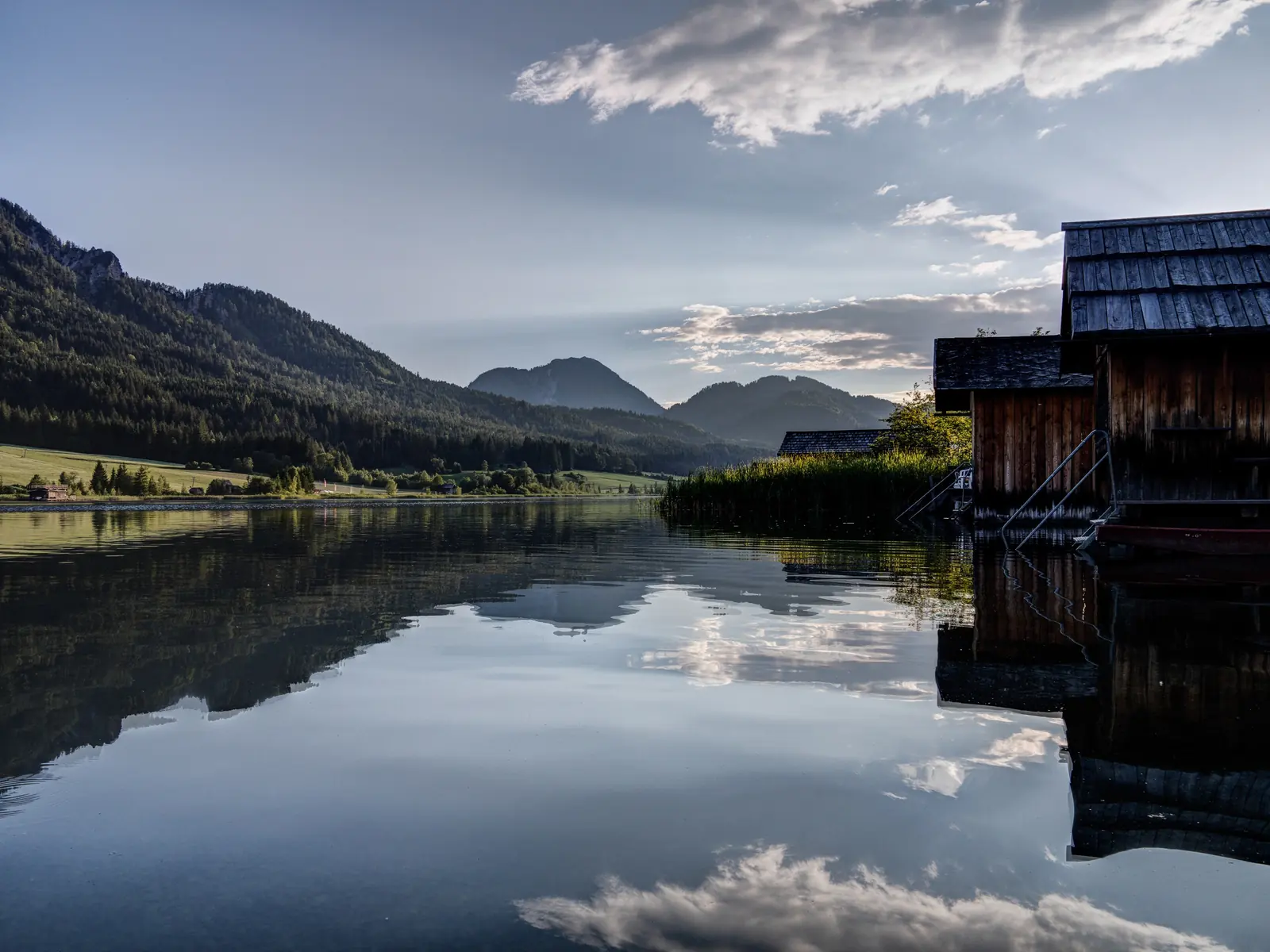 Bootshütte am Weissensee, die Berge spiegeln sich im glatten Wasser